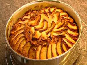 Appeltaart of appelcake gebakken in een springvorm met stukjes appel in het deeg en schijfjes appel erboven op.